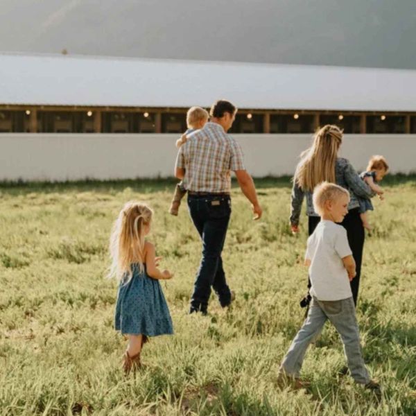 A family walking across a field beside an Armstrong barn
