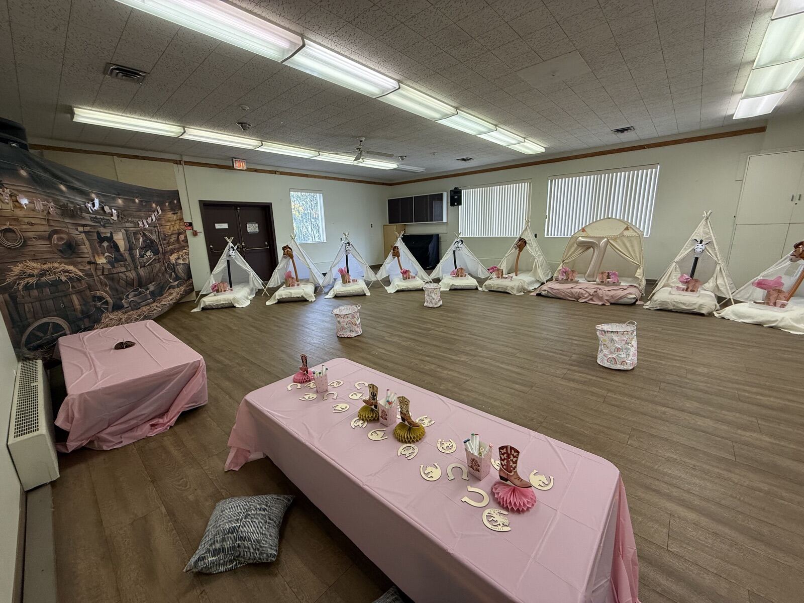 Pink-covered low tables in front of a line of teepees along the main hall wall