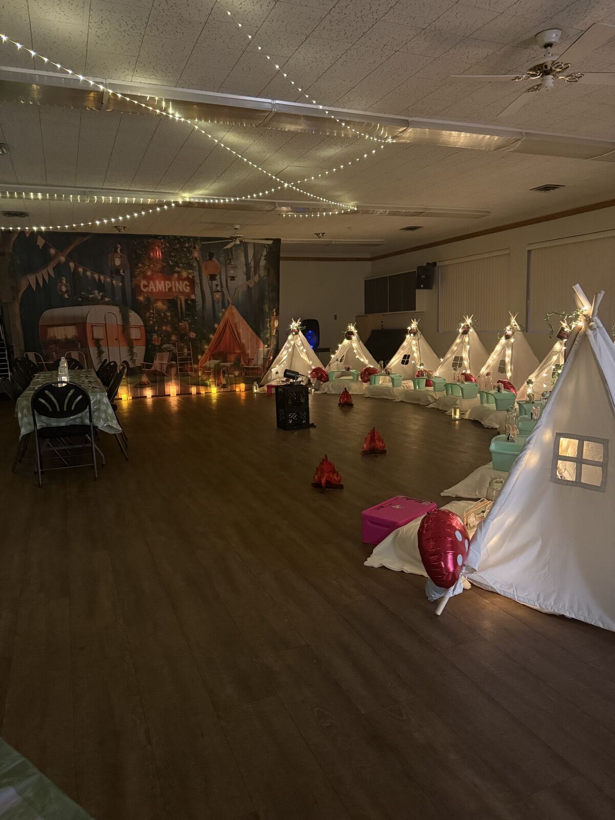 White teepees under string lights in the main hall of the Armstrong Odd Fellows Hall