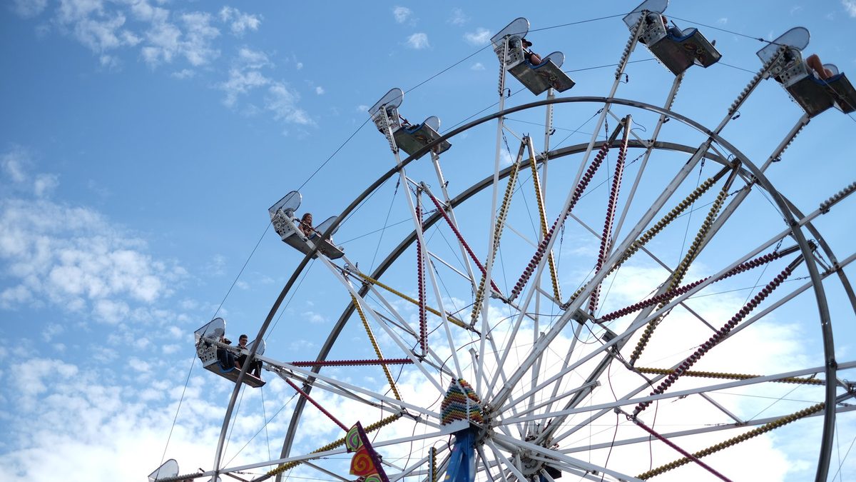 Riders on a ferris wheel against a blue sky on the midway at the IPE in Armstrong, BC